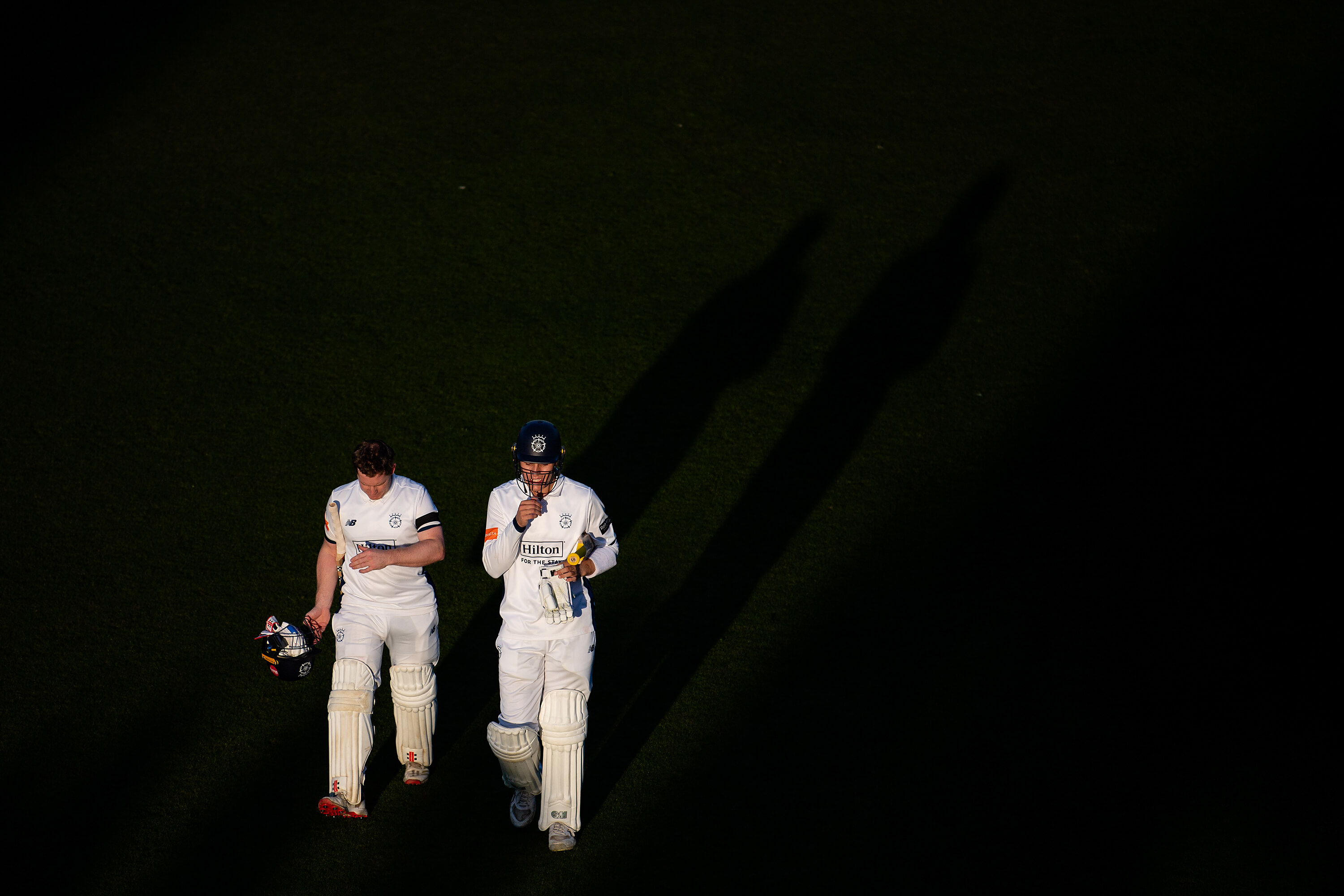 Ben Brown and Toby Albert walk off the pitch as shadows close in following a day's play at Utilita Bowl